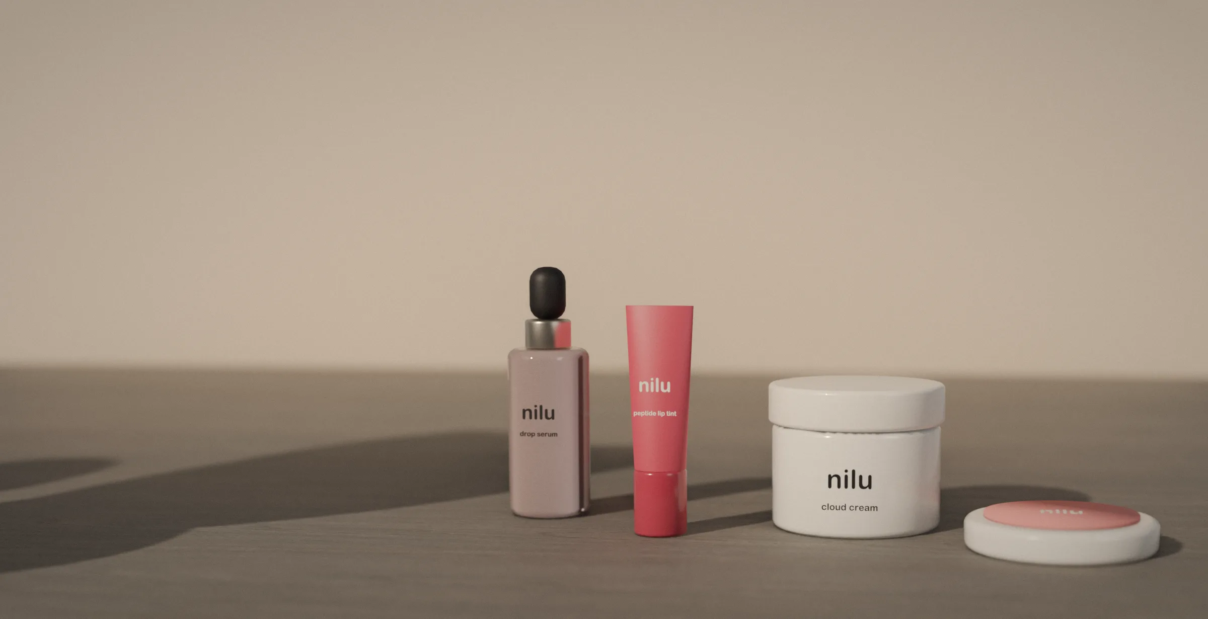 The four nilu products standing together in low morning sun: drop serum, tint, cloud cream and the bloom compact